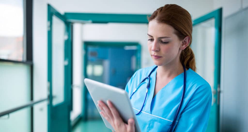 Healthcare provider using a tablet to review a patient's electronic health record (EHR).